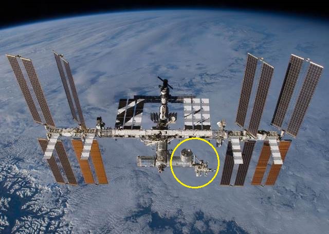図1：　国際宇宙ステーション(International Space Station: ISS) 左舷の一番大きなモジュール複合体（黄色の輪の中）が日本実験棟「きぼう」 （NASA提供）