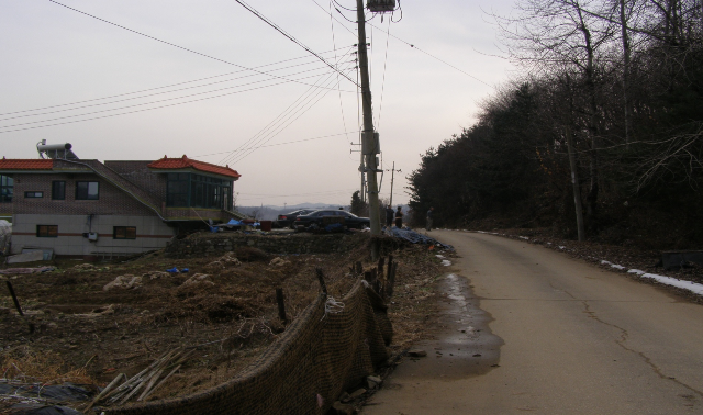 2007年12月に対人地雷除去研究所のキム所長によって地雷が発見された地域（右側の土地）。左側が土地の所有者の家