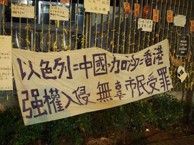「イスラエル＝中国、ガザ＝香港」と訴える、政府庁舎前の広場の柵に掲げ られた横断幕（撮影：倉田明子）